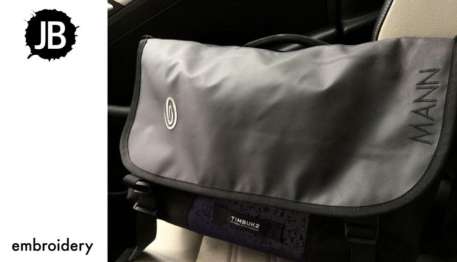 Embroidery on a black messenger bag as an example of bag embroidery placement